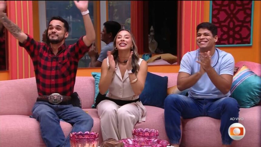 João Pedro batendo palma ao lado de Renata que também bate palma e Guilherme que sorrir, sentados no sofá do BBB 25 ao descobrir que estão na final