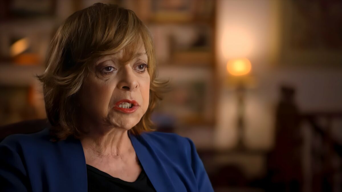 Gloria Perez de terninho azcul com a boca aberta gravando depoimento para documentário