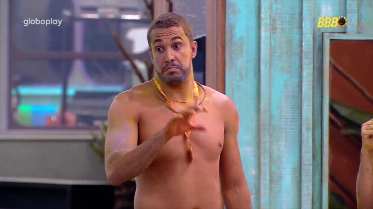 Maike todo pintado de fumaça colorida do Sincerão, no gramado da casa do BBB 25 com a mão levantada