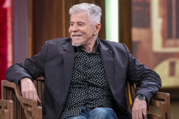 Miguel Falabella de calça jeans e blazer preto sentado em uma cadeira