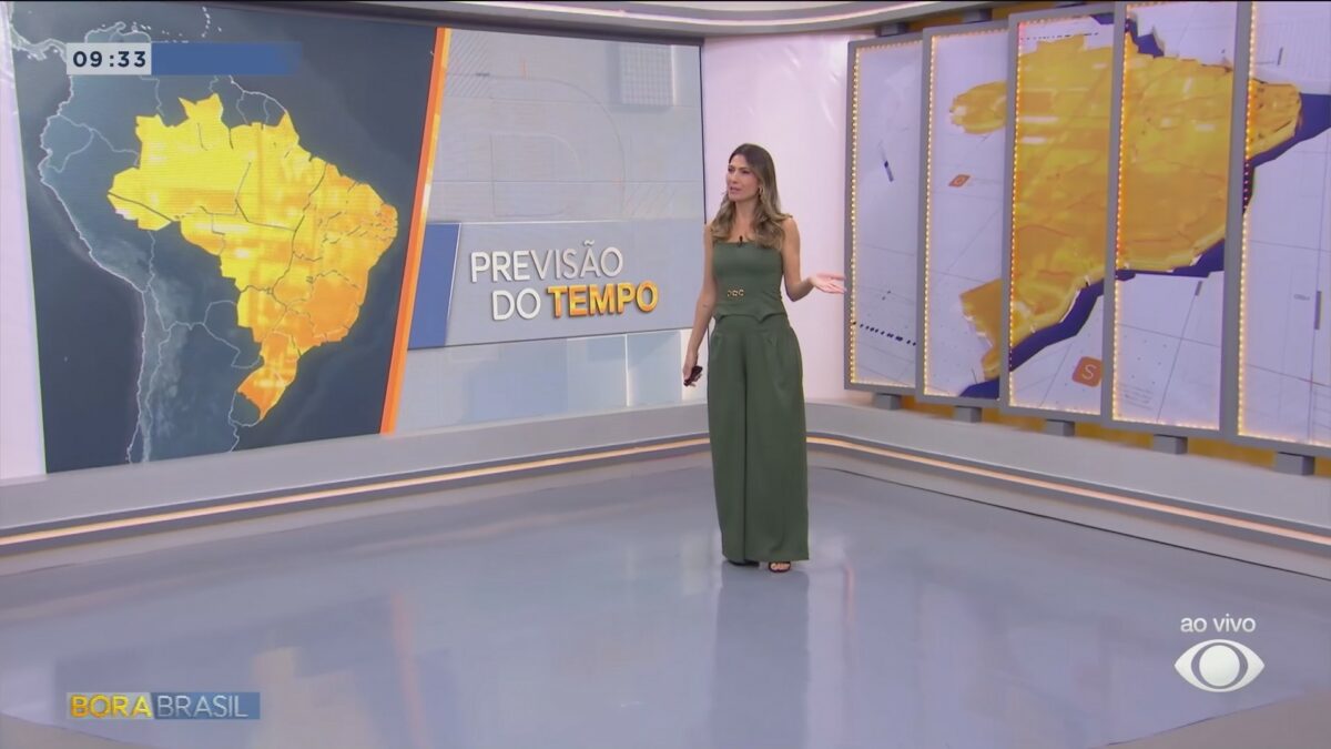 Patrícia Rocha em frente ao telão que carrega o mapa do Brasil, em amarelo, na Previsão do Tempo