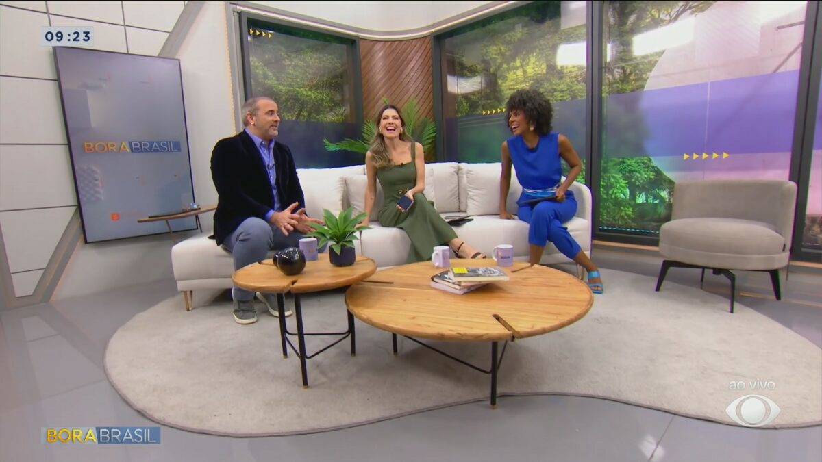 Trio de apresentadores se divertem no novo espaço do cenário do Bora Brasil, eles estão sentados no sofá