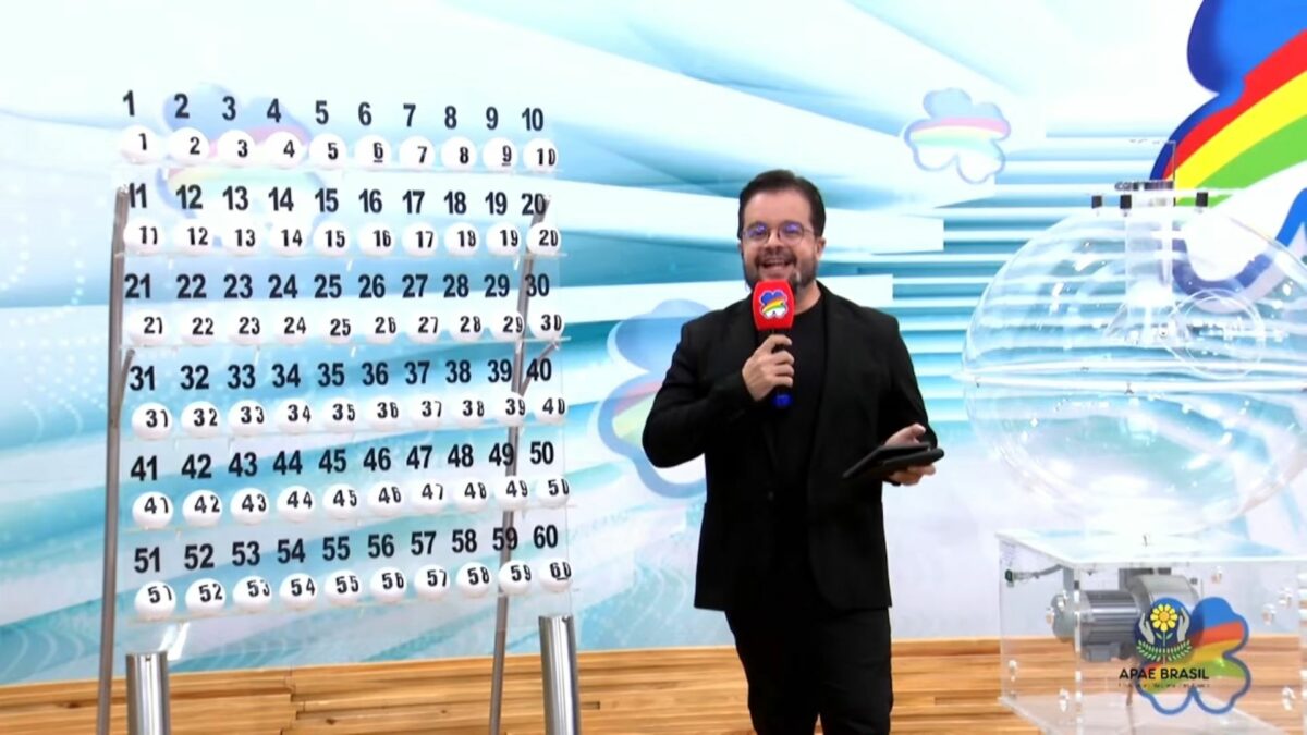 Apresentador do Pernambuco dá Sorte em frente ao painel com as bolas do sorteio