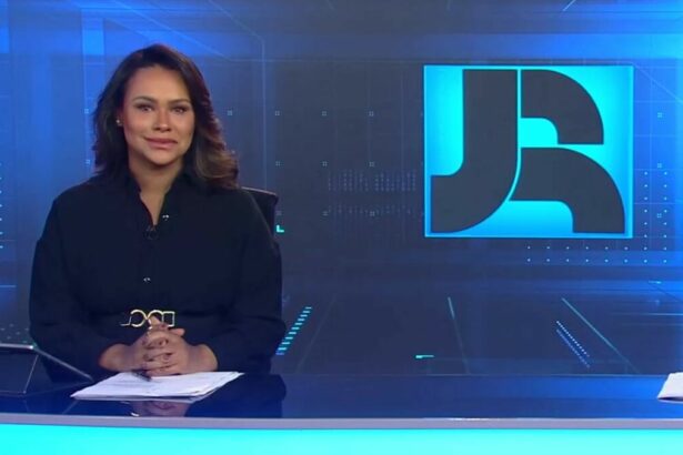 Salcy Lima veste preto, está sorrindo, sentada na bancada do Jornal da RECORD