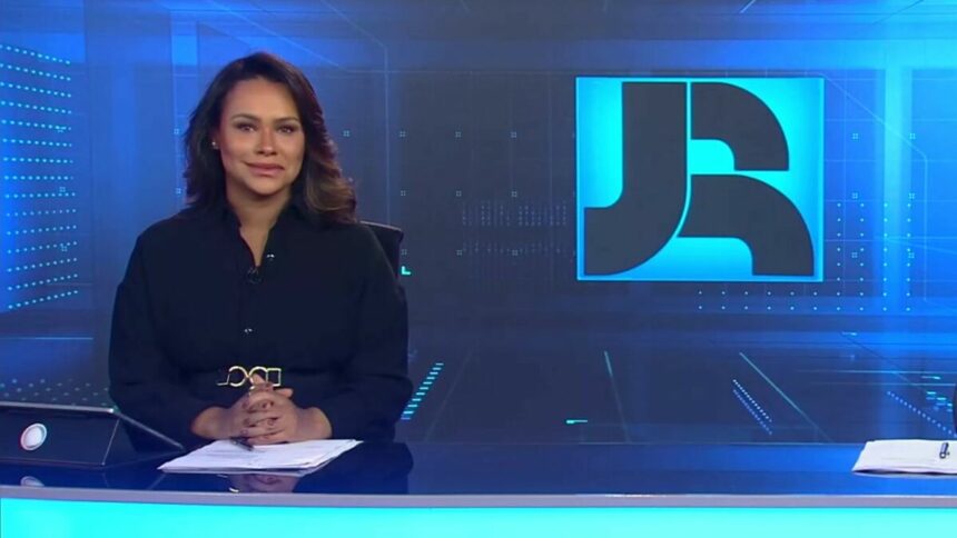 Salcy Lima veste preto, está sorrindo, sentada na bancada do Jornal da RECORD