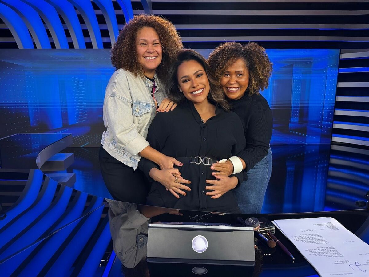 Duas maquiadoras acariciam a barriga de grávida de Salcy Lima