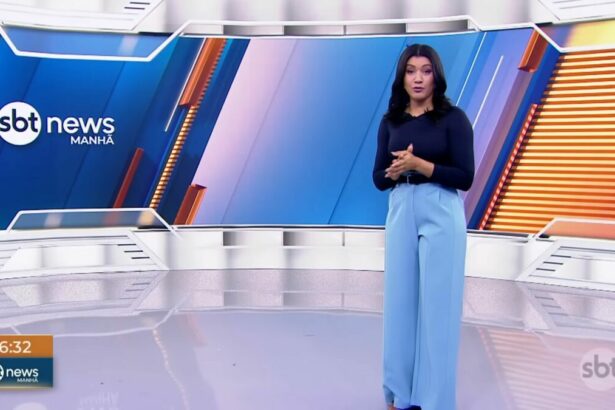 Dani Brandi em pé no centro no cenário do SBT News Manhã