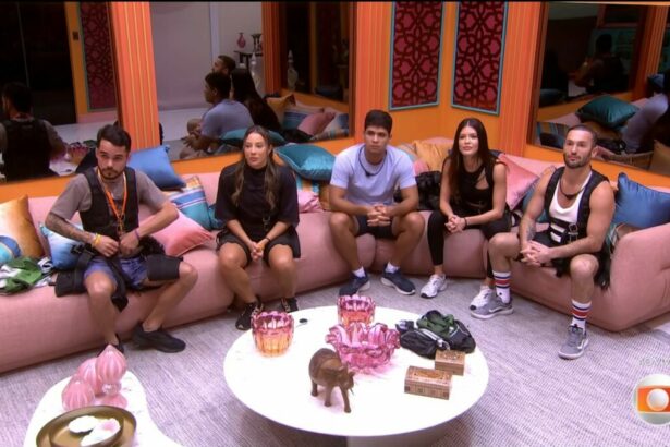João Pedro, Renata, Guilherme, Vitória Strada e Diego Hypolito sentados no sofá da sala do BBB 25 olhando para o telão e com roupa para disputar prova