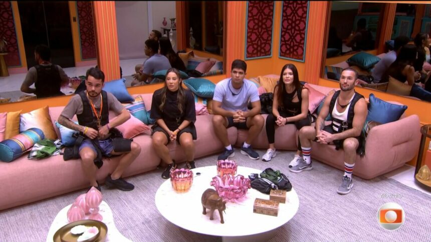 João Pedro, Renata, Guilherme, Vitória Strada e Diego Hypolito sentados no sofá da sala do BBB 25 olhando para o telão e com roupa para disputar prova