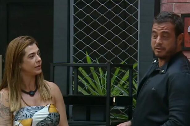 Adriana e Dhomini em frente ao quadro da divisão de quartos no Power Couple Brasil 7