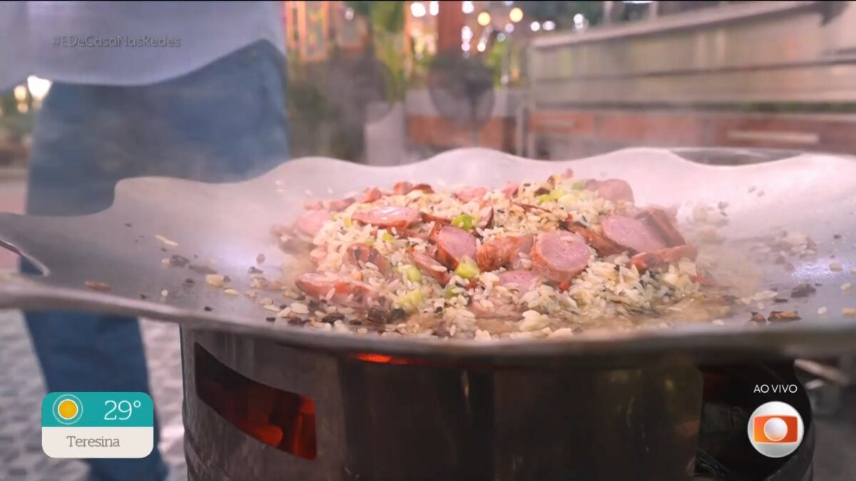 Arroz com linguiça e mandioquinha na brasa na tigela de um fogão a lenha do É de Casa