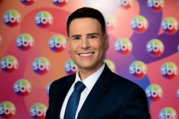Luiz Bacci em frente ao painel com os logos do SBT