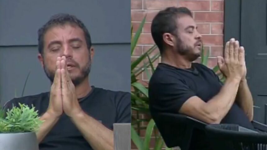 Dhomini com os olhos cerrados e as mãos fechadas, fazendo uma oração no Power Couple