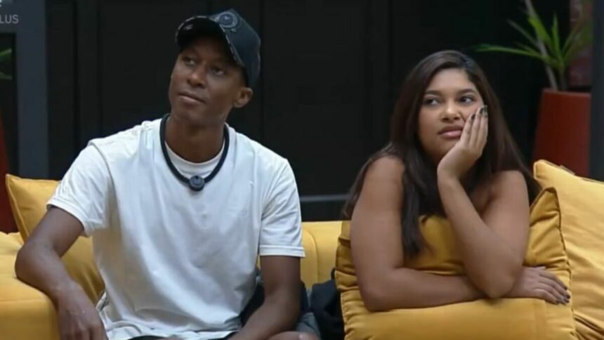 Emilyn e Neguinho sentados no sofá do Power Couple