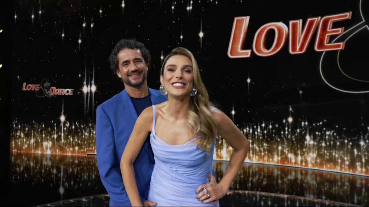 Felipe Andreoli e Rafa Brites em pé, no palco do Love e Dance, eles estão sorridentes