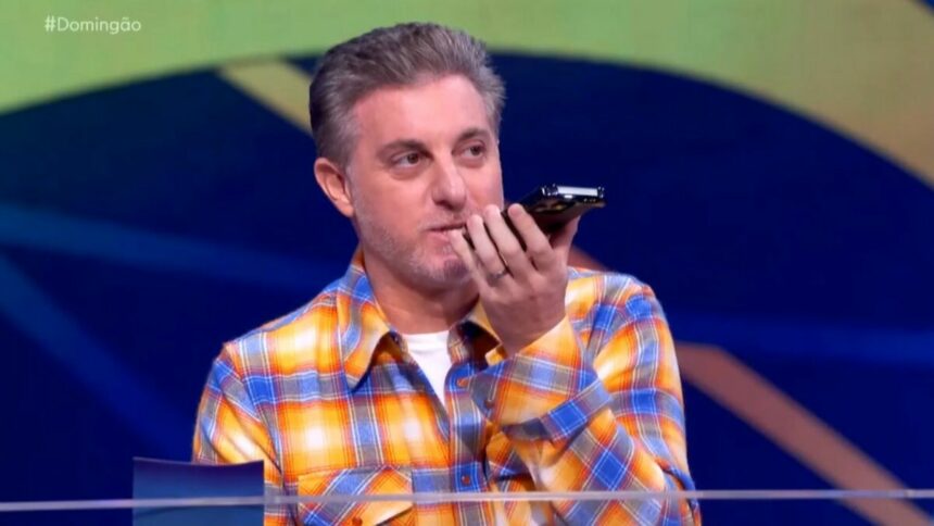 Luciano Huck atendendo o celular durante gravação do Domingão