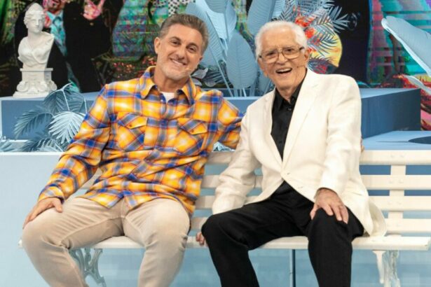 Luciano Huck e Carlos Alberto de Nóbrega sentados em um banco de praça no Domingão