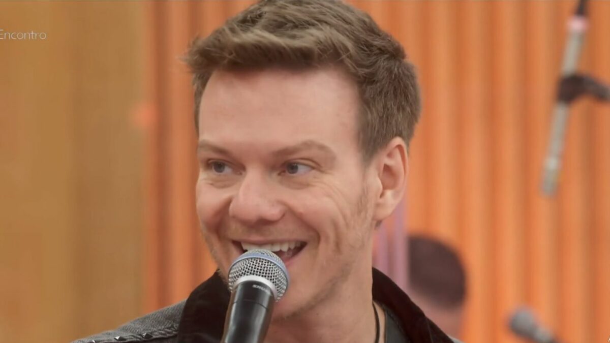 Michel Teló sorridente em trecho de participação no Encontro