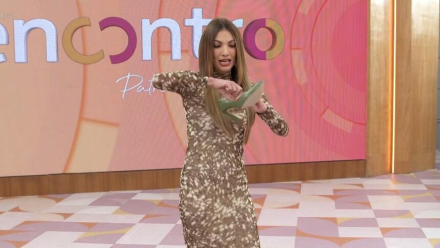Patrícia Poeta com um sapato na mão no cenário do Encontro