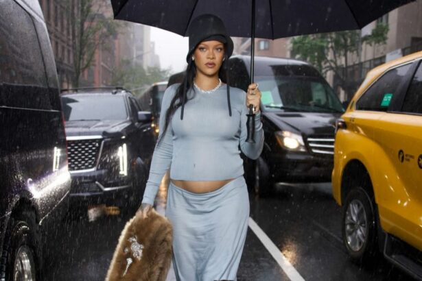 Rihanna veste look azul claro com barriga de grávida a mostra e segura guarda-chuva em uma avenida de Nova Iorque