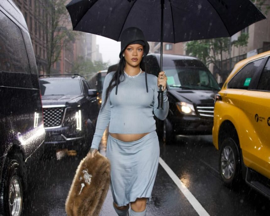Rihanna veste look azul claro com barriga de grávida a mostra e segura guarda-chuva em uma avenida de Nova Iorque