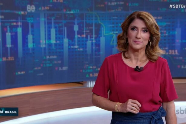 Simone Queiroz no cenário do SBT Brasil, vestida de blusa vermelha e saia azul