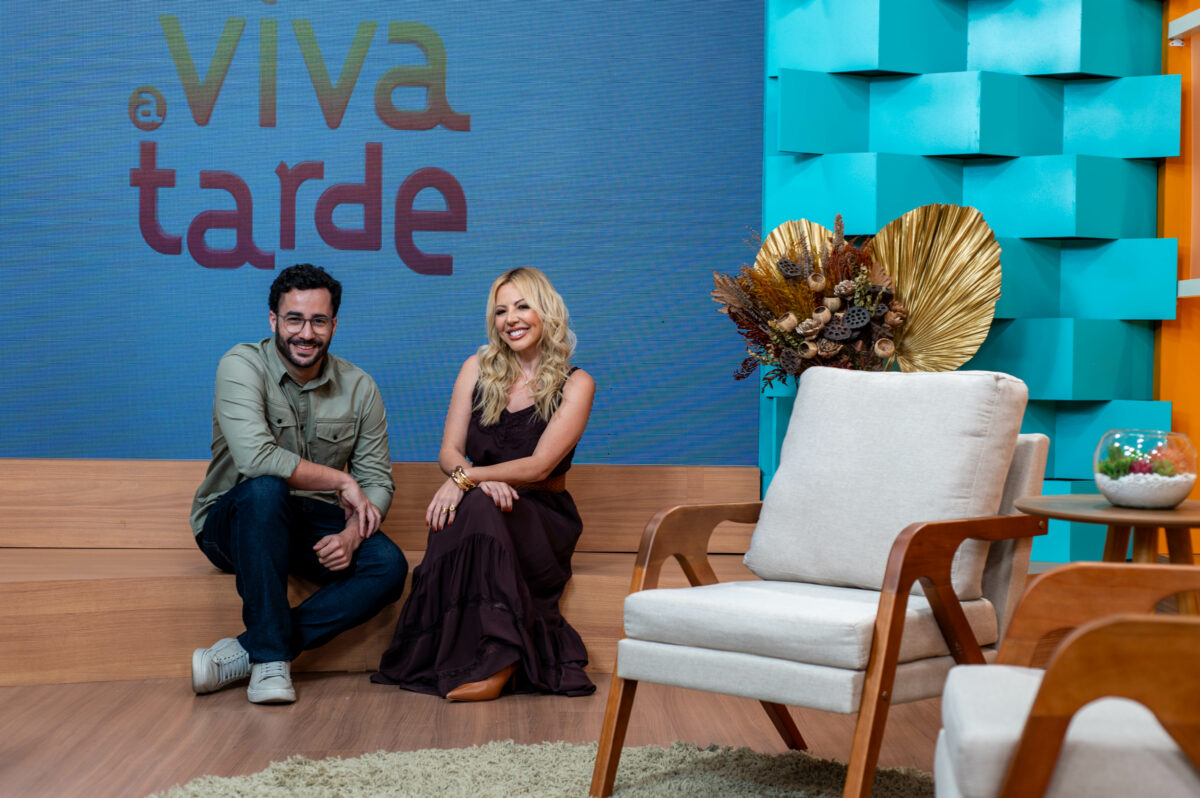 Apresentadores do Viva a Tarde, sentados no cenário do novo programa da TV Aparecida. Abiane Souza e Guilherme Machado estão sorrindo
