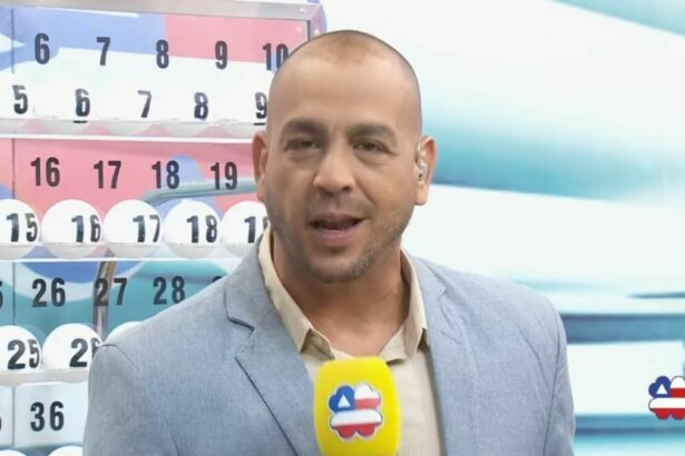 Apresentador do Bahia dá Sorte em frente ao painel com as bolas do sorteio de 11 de maio. Ele segura um microfone amarelo
