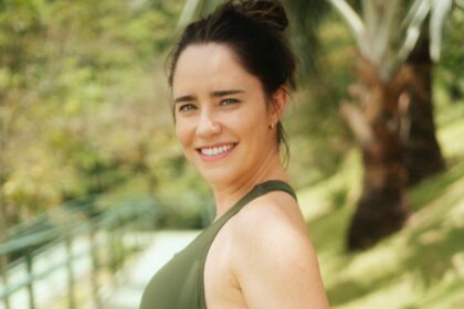 Fernanda Vasconcellos de top verde em um lugar que parece ser um resort