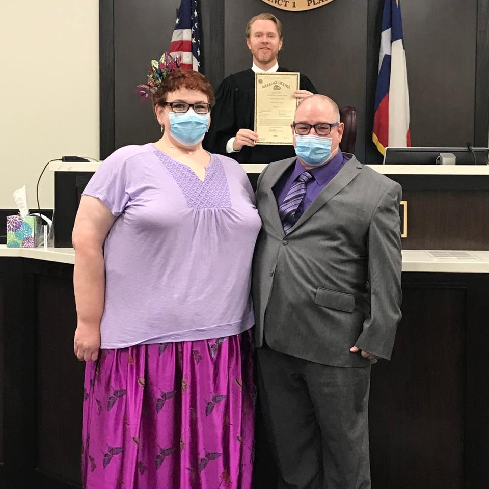 Holly e o marido usando máscaras em um local que parece ser um tribunal