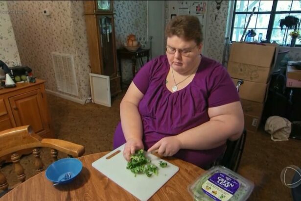 Holly, de blusa vinho, sentada em uma cadeira de rodas cortando alfaces em cena do Quilos Mortais