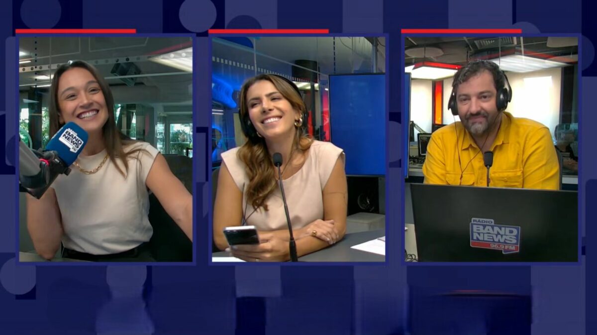 Jornalistas Carla Bigatto, Sheila Magalhães e Luiz Megale sorridentes no estúdio da rádio BandNews FM