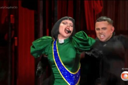 Lady Gaga canta com um vestido verde e azul e amarelo