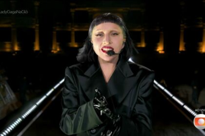 Lady Gaga veste preto, e caminha no palco, no encerramento do show. Ela olha para câmera da transmissão do Globoplay