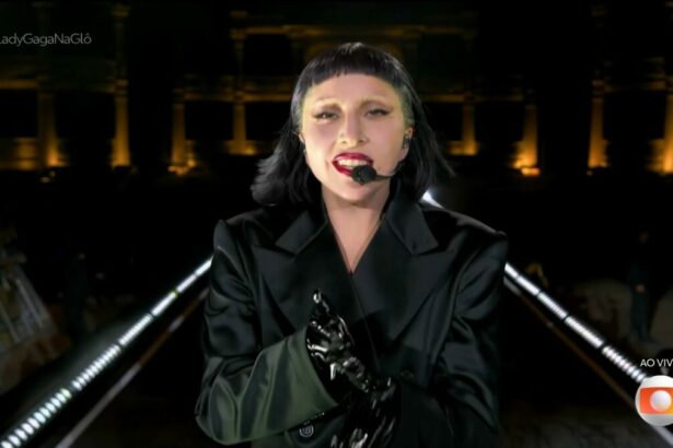 Lady Gaga veste preto, e caminha no palco, no encerramento do show. Ela olha para câmera da transmissão do Globoplay