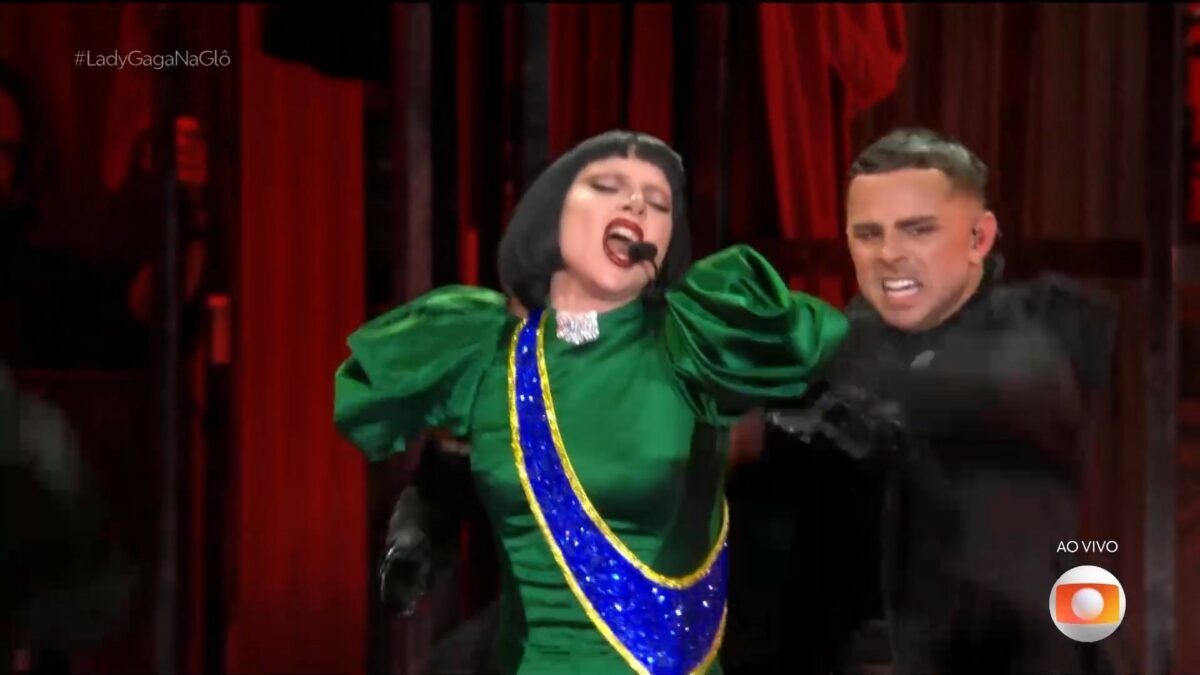 Lady Gaga canta com um vestido verde e azul e amarelo