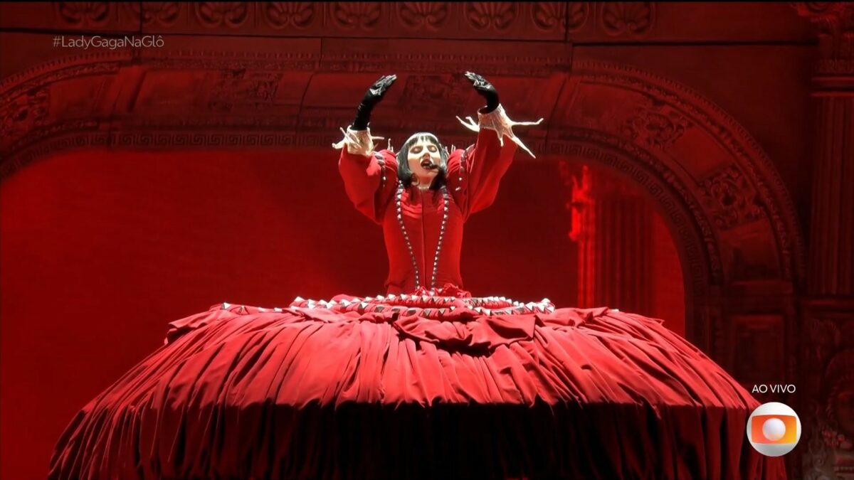 Lady Gaga no gigante vestido vermelho olhando para o alto