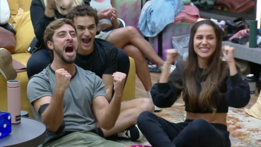 Eike e Nat gritam e fazem sinal de comemoração sentados na sala da Mansão Power Couple Brasil 7 antes do veto em Silvia e André