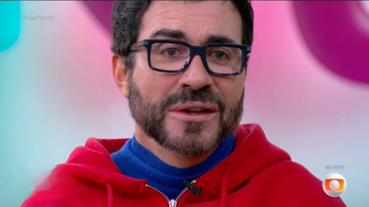 Padre Fábio de Melo com camisa azul e casaco vermelho chorando no Mais Você