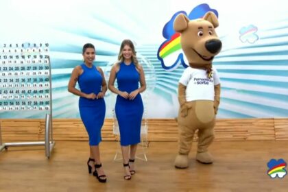 Assistentes de palco vestem azul, posicionadas ao lado do painel com as bolas e o mascote do sorteio do Pernambuco dá Sorte