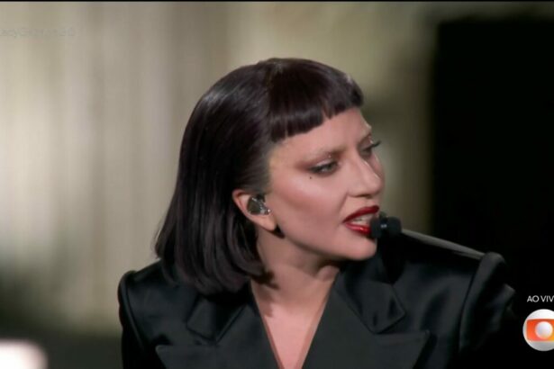 Lady Gaga, veste preto, olha para o lado direito do palco enquanto toca piano em show no Rio de Janeiro