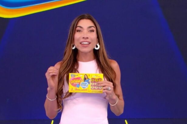 Patricia Abravanel sorrindo e segurando o bilhete do quarto sorteio da Tele Sena de Mães 2025. Ela veste um vestido branco.