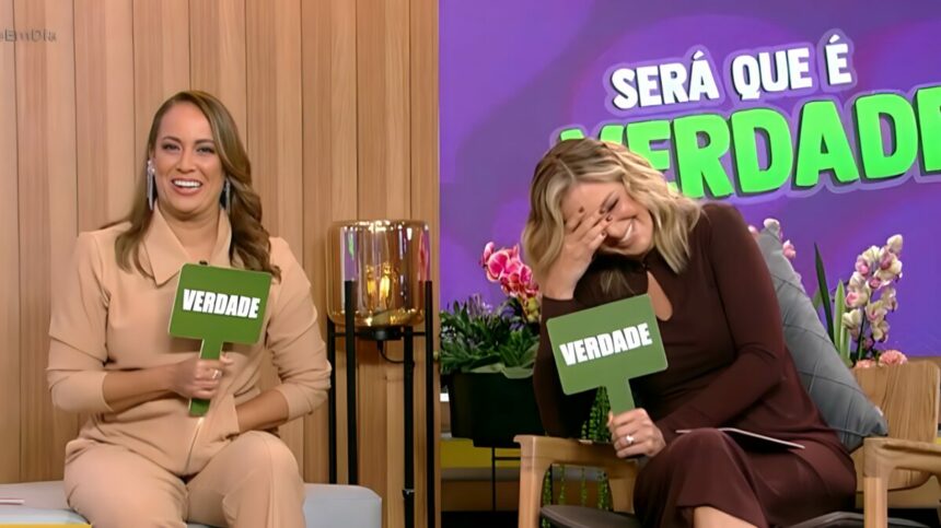 Renata Alves segura plaquinha de "Verdade" ao lado de Ticiane Pinheiro que gargalha, também segurando a plaquinha no cenário do Hoje em Dia