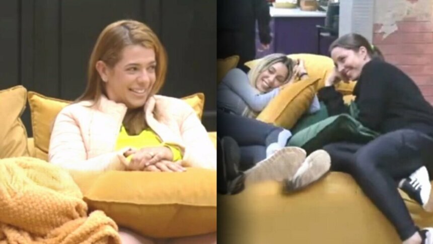 Adriana sentada no sofá da Mansão do Power Couple e sorrindo para Carol que está na outra ponta
