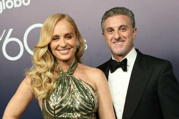 Angélica, de vestido verde brilhante, e Luciano Huck, de smooking, em foto posada juntos e sorridentes nos bastidores do especial de 60 anos da Globo