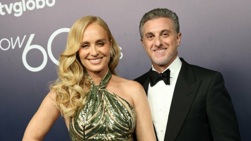 Angélica, de vestido verde brilhante, e Luciano Huck, de smooking, em foto posada juntos e sorridentes nos bastidores do especial de 60 anos da Globo