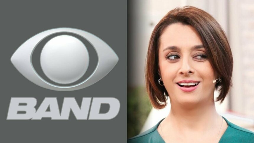 Logo da Band ao lado de Catia Fonseca que está de blusa verde e olhando para o lado, em pé, no cenário do Bom Dia & CIA