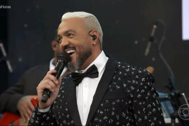 Belo, de terno brilhoso e gravata borboleta, sorrindo no palco do Altas Horas