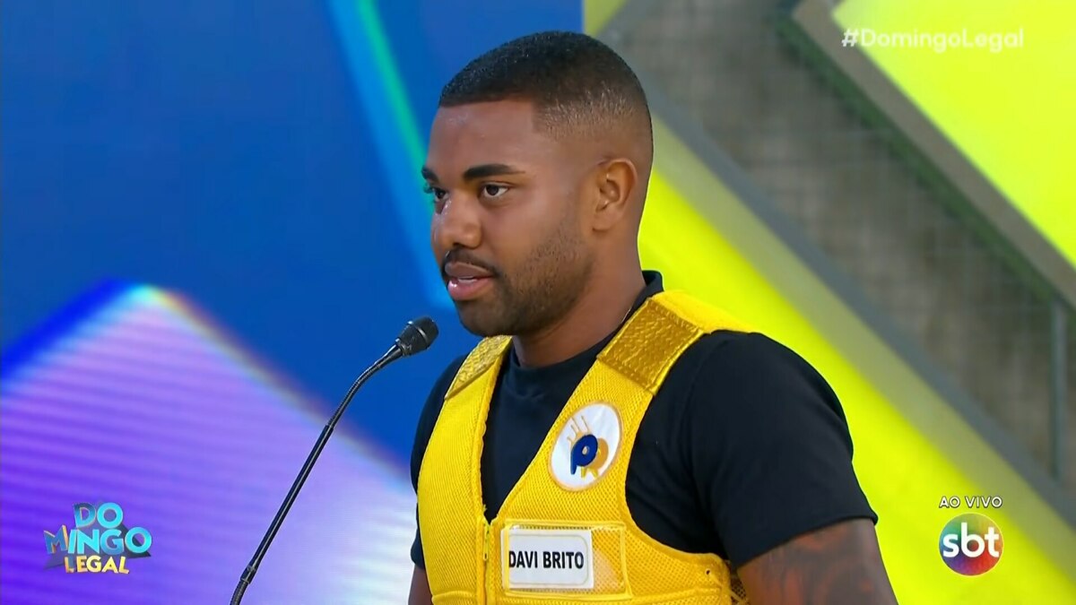 Davi Brito, vestido de colete amarelo, em trecho do Passa ou Repassa no Domingo Legal