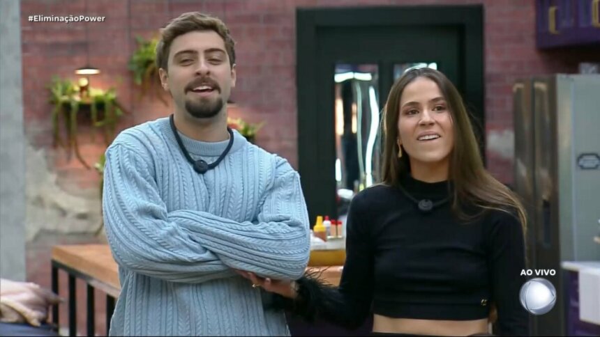 Eike cruza dos braços ao lado de Nat enquanto comemoram Herança da DR na sala do Power Couple Brasil 7